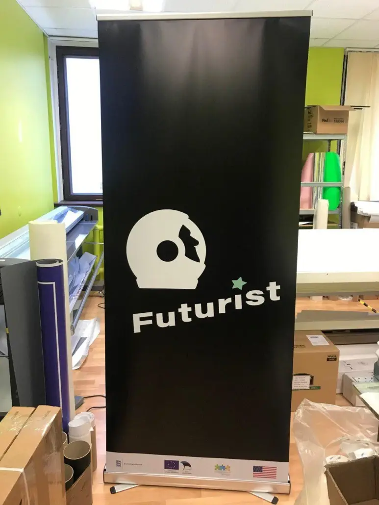 Must roll-up stend Futurist logo ja valgete kirjadega rohelise seinaga ruumis